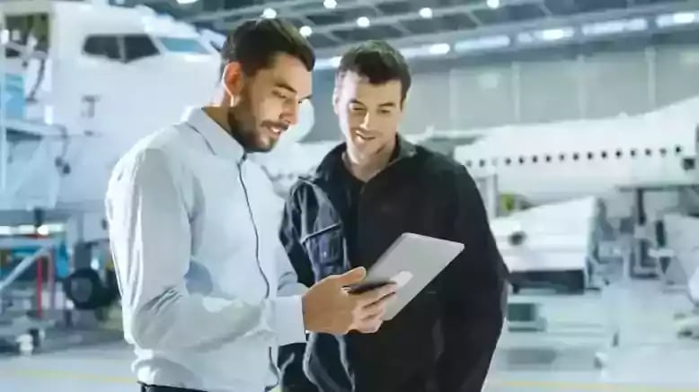 660d3e3dfac9c4d8c27a9d80_2 men watching tablet in hangar